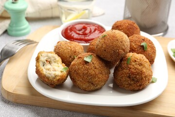 Delicious fried croquette balls with parsley and ketchup on grey textured table, closeup