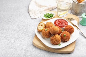 Delicious fried croquette balls with parsley and ketchup on grey textured table, closeup. Space for text