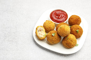 Delicious fried croquette balls with parsley and ketchup on grey textured table, closeup. Space for...