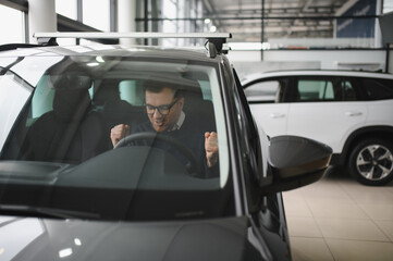 Young man is choosing a new vehicle in car dealership