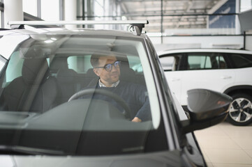 Young man is choosing a new vehicle in car dealership