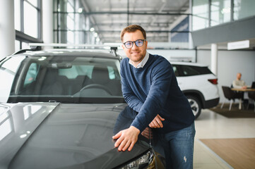 I got a new car today. Portrait of a happy mature man smiling posing near his new car at the local...