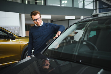 Young man is choosing a new vehicle in car dealership