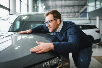 Young man is choosing a new vehicle in car dealership
