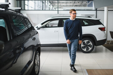 Young man is choosing a new vehicle in car dealership