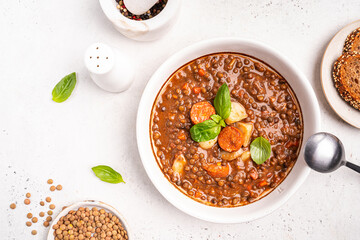Traditional Spanish dish of lentil stew with chorizo and potatoes on a white background. Top view...