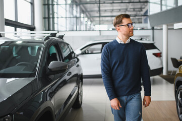 Young man is choosing a new vehicle in car dealership