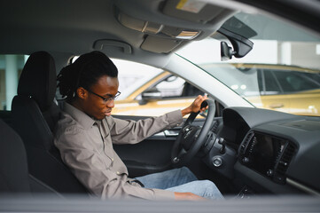 Young african american man is choosing a new vehicle in car dealership
