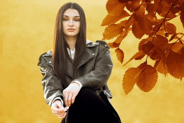 portrait of Beautiful young brunette latin hispanic brunette woman lady girl looking at camera in autumn seasonal park. Sunny golden yellow elm tree branch with leaves on autumn blurred background