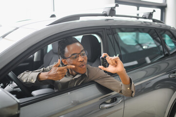 Young african american man is choosing a new vehicle in car dealership