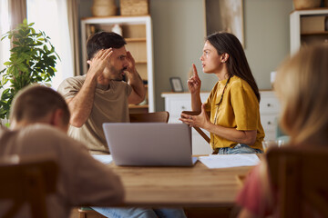Frustrated parents talking about financial bills during e-banking over a computer at home.