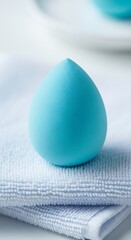 Turquoise Makeup Sponge on Soft White Towel, Beauty Still Life