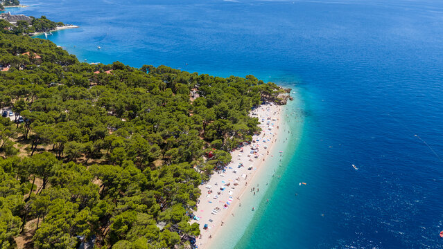 Stunning drone shot of Punta Rata Beach in Brela, Croatia, filled with tourists enjoying the crystal-clear Adriatic Sea.