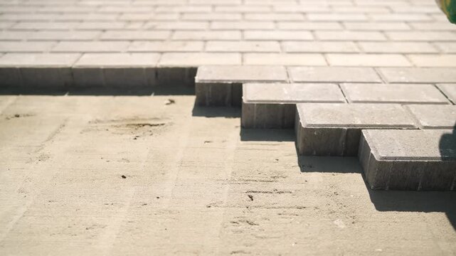 Construction worker laying paving stones on sand