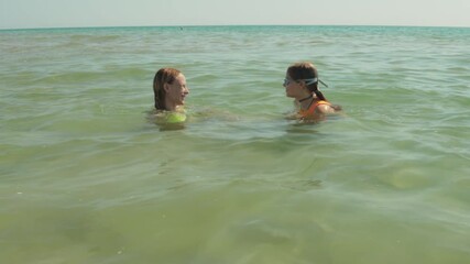Teenage daughter and mother laughing, playing, and bonding while swimming in turquoise ocean waters during summer vacation. Lifestyle, vacation, tourism,nature, active life - Powered by Adobe