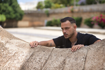 Portrait of young, brunette, Hispanic, modern man in black crochet shirt, sad and depressed, with...