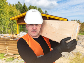 Man builder carries boards. Worker builds country house from wood. Foreman from construction team....
