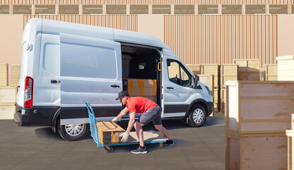 Delivery worker unloading cardboard boxes from van using cart at warehouse yard with wooden crates. Parcel transport, shipping, delivery service, logistics operations.