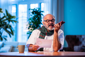 Elderly Indian man calls CA to talk about tax report while sitting at home table