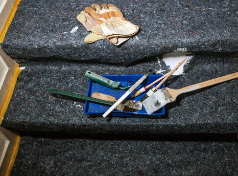 Konzept Renovieren, Lackieren, Streichen und Malen in einer Wohnung: Blick auf Pinsel, Farbe, Kelle, Spachtel, Handschuhe, Abdeckung und weitere Utensilien auf Malervlies, Copyspace, selektiver Fokus
