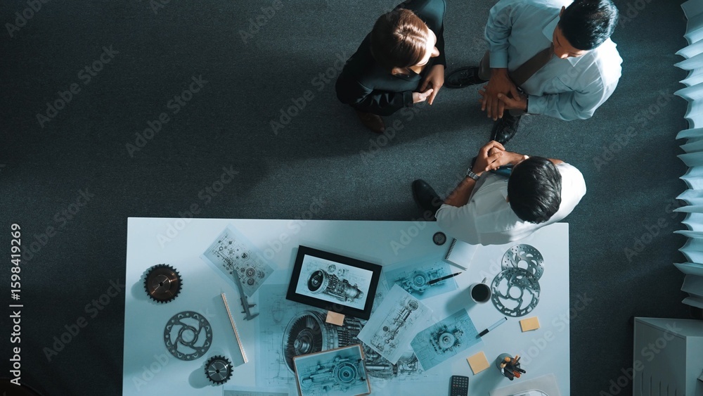 Poster top down view of smart engineer talking about turbine engine design while standing at meeting table 