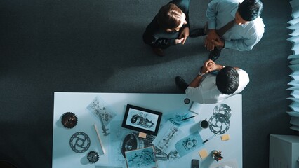 Top down view of smart engineer talking about turbine engine design while standing at meeting table...