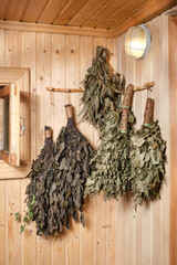 Dry brooms in the bath are hanging on the wall. 