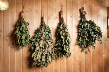 Birch and oak brooms on a bath wall.