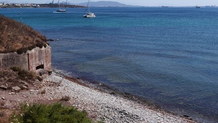 Coastal shore with a bunquer of World War II. In the background are shipyards
