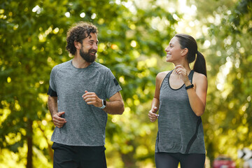 Two individuals share a lighthearted run through a vibrant park, filled with greenery, highlighting...