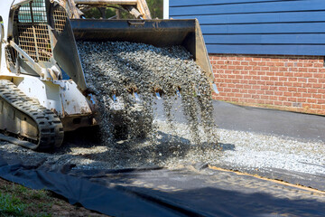 Construction equipment pours gravel onto ground at home improvement project during works place