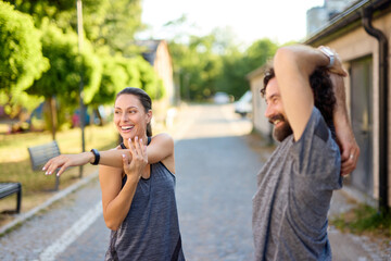 Two friends engage in stretching exercises after a morning jog in a tranquil outdoor park setting....