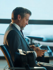 Businessman using smartphone in airport lounge waiting for flight departure