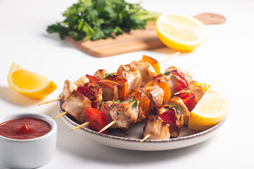 Delicious grilled chicken skewers with capsicum, lemon, salad and ketchup on a plate over the table. Chicken kebab. Healthy food concept.