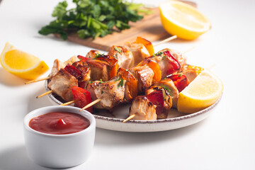 Delicious grilled chicken skewers with capsicum, lemon, salad and ketchup on a plate over the table. Chicken kebab. Healthy food concept.