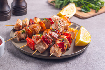 Delicious grilled chicken skewers with capsicum, lemon, salad and ketchup on a plate over the table. Chicken kebab. Healthy food concept.