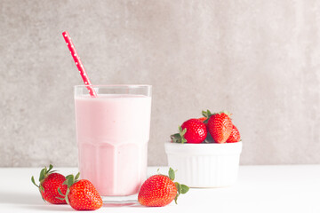 Glass of fresh strawberry milkshake, smoothie and fresh strawberries on white and wooden background. Healthy food and drink concept.