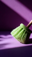 A bright green brush with wooden handle casting shadows on a purple surface in striking contrast.