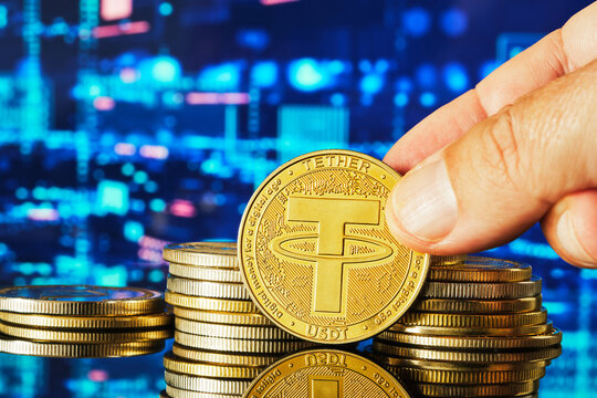 Hand Holding a Tether Coin Above a Stack of Cryptocurrency Coins With Digital Background