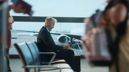 Businessman using smartphone in airport lounge waiting for flight departure