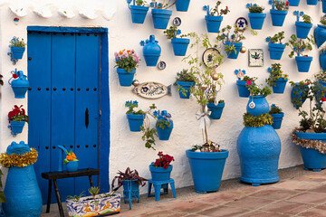 Fachada de casa con puerta de madera y maceteros azules.