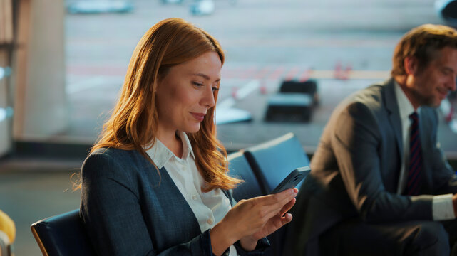 Businesswoman using smartphone in airport lounge waiting for flight - Powered by Adobe