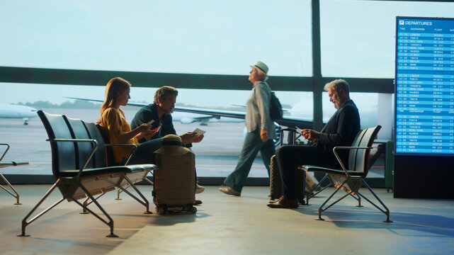 Passengers waiting in airport lounge checking tickets and departures board