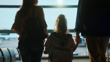 Family looking at airplane taking off from airport terminal window
