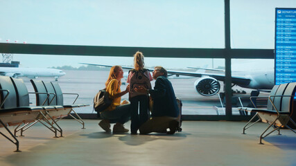 Family looking at airplane through window in airport lounge