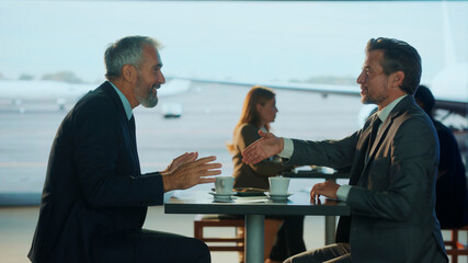 Businessmen shaking hands in airport lounge during meeting