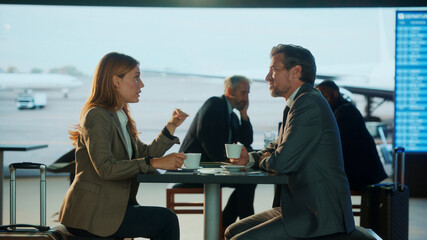 Business people discussing at airport lounge bar while drinking coffee