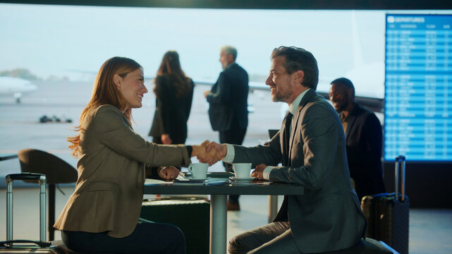 Business people shaking hands in airport lounge before departure