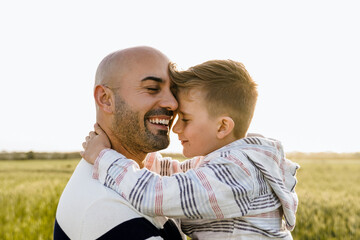 Father hugging child in countryside at sunset – Warm family moment in autumn field