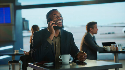 Happy businessman talking on phone in airport lounge